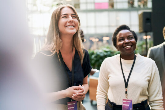 Female corporate professional happily interacting with attendees at networking event at convention center