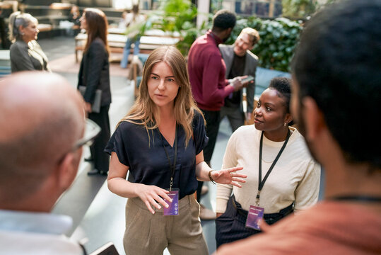 High angle view of female business expert exchanging ideas with executives regarding connectioneering during event at co