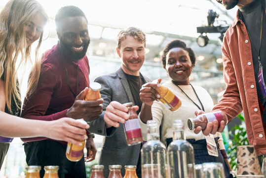 Male and female delegates choosing juice bottle at networking event in convention center