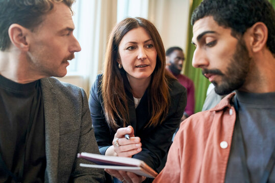 Female business professional sharing notes with male associates while attending seminar in convention center
