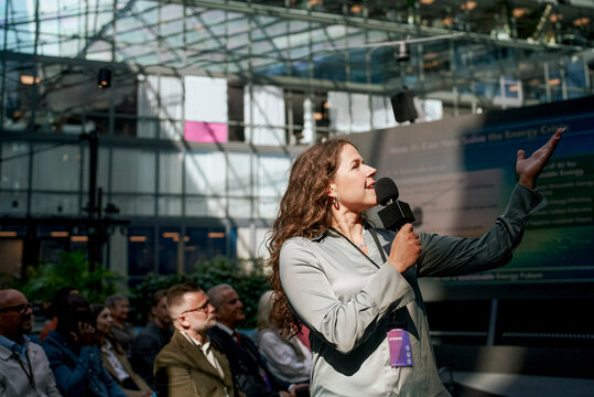 Female mature keynote speaker giving presentation at business summit in convention center