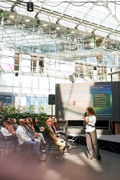 Male and female business associates listening to speaker while attending seminar at convention hall