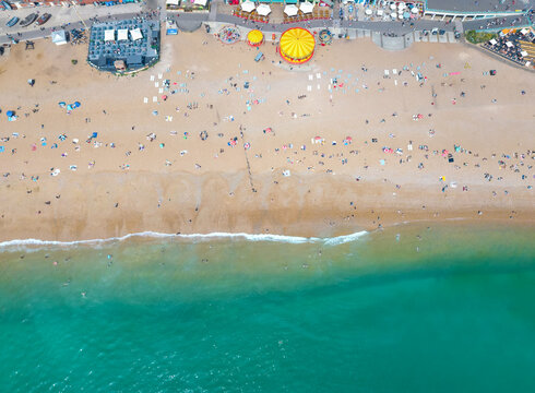 Aerial overhead view of the beach at Brighton, England, during a sunny day with people enjoying the fresh ocean