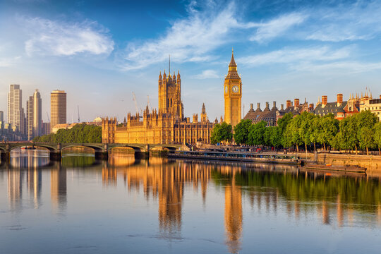 Beautiful summer sunrise view of the Westminster Bridge and Palace with Big Ben clocktower in London, England, with reflections in the River Thames