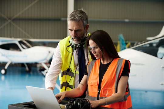 Aviation engineers collaborating on laptop during aircraft maintenance