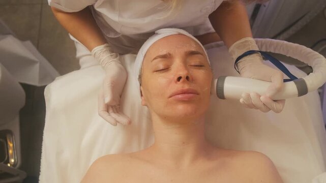Relaxed woman getting a cold facial massage with a cryo machine at a beauty salon