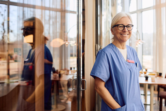 Portrait of smiling senior female physician standing with hand in pocket