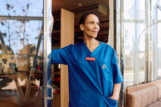 Confident senior female physician looking away while standing with hand in pocket