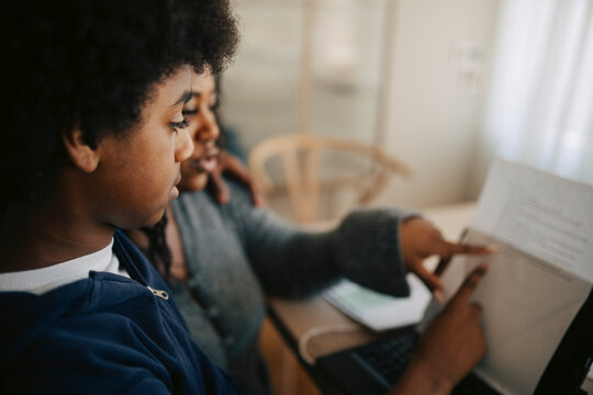 Boy taking guidance from mother during home study session