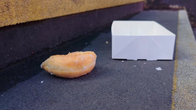 Abandoned pastry on stairway with empty food packaging in close urban perspective. Street life symbolism reflecting deprivation hunger economic struggle and homelessness awareness concept. Social