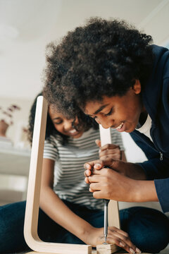 Smiling boy making DIY furniture with sister at home