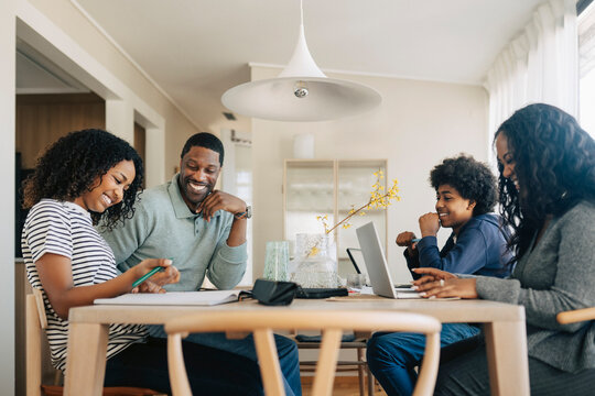 Happy family balancing professional work and kids education while sitting at same table