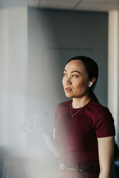 Businesswoman looking sideways while talking on speaker phone at office