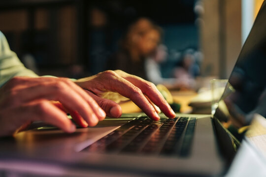 Close-up of businessman typing mail on laptop while working at coworking space