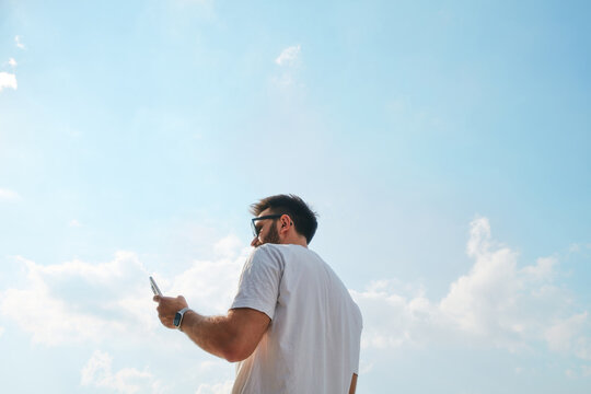 Man using smartphone against blue sky background