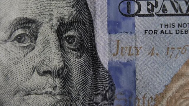 100 dollar US bill with portrait of Benjamin Franklin and blue holographic security stripe on obverse of banknote close-up