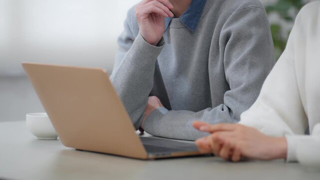 部屋でノートパソコンを見る男女カップル