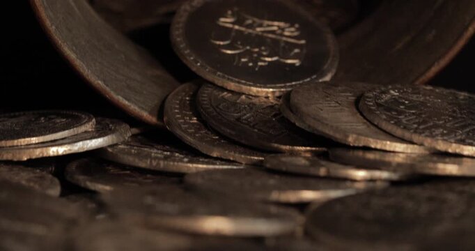 Close-up of old imitation Islamic coins pouring into a treasure pile