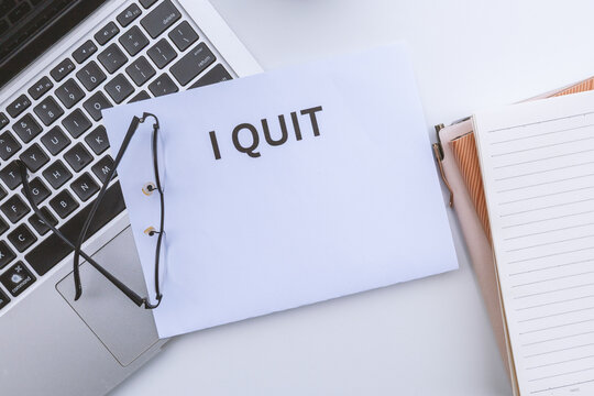 Flat lay conceptual composition of career change and workplace burnout featuring an explicit "I Quit" notice on a modern corporate desk