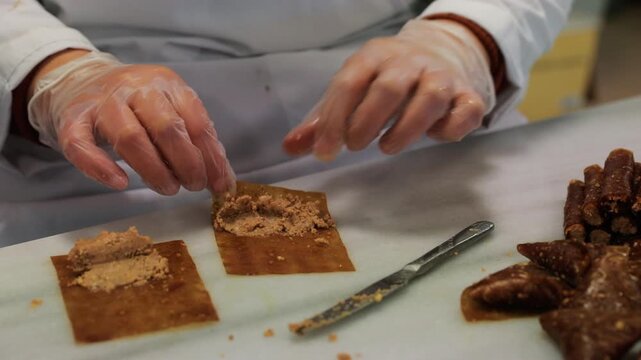 Close-up detail of a professional chef preparing traditional Turkish walnut-filled pestil rolls.