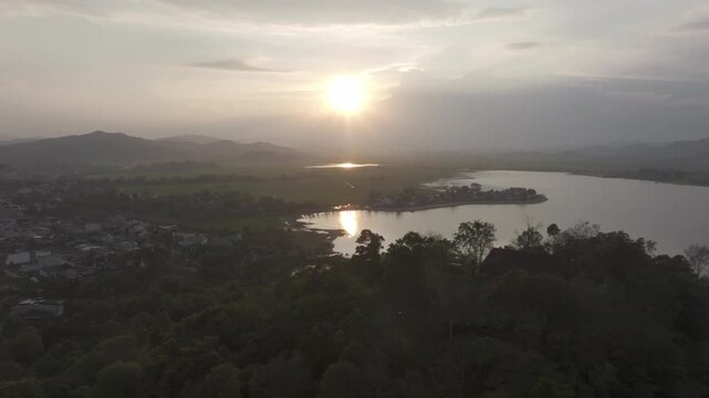 Sunset over Lak Lake in Lien Son Lak Commune, Dak Lak Province, Vietnam, featuring traditional wooden boats on the lake and peaceful rice fields surrounded by the Central Highlands landscape.