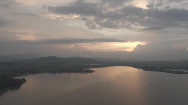 Sunset over Lak Lake in Lien Son Lak Commune, Dak Lak Province, Vietnam, featuring traditional wooden boats on the lake and peaceful rice fields surrounded by the Central Highlands landscape.