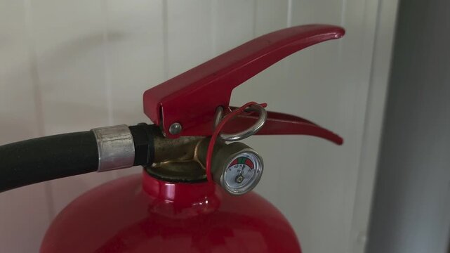 Close-up of a red fire extinguisher with pressure gauge and hose