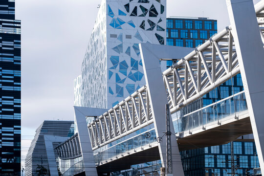 The Akrobaten bridge walkway rises through Oslo, Norway Barcode, where patterned facade glass and steel frame the modern district edge