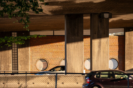 cars pass beneath an Oslo, Norway underpass where concrete columns, brick surfaces and shadow define a parking street layer below the city