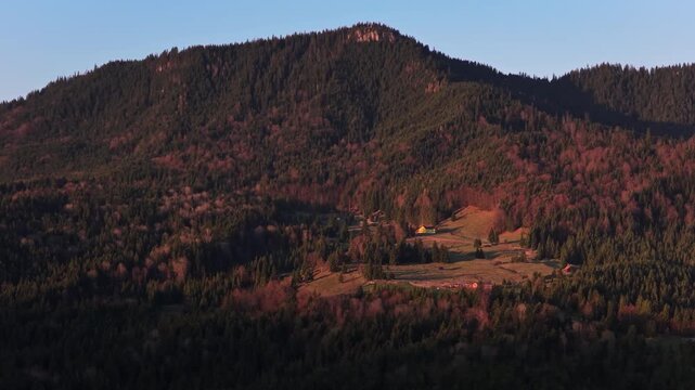 Aerial drone view of a rounded forested hill with open patches and rural houses, typical of the mountainous terrain near Vatra Dornei, Romania, close to the Vatra Dornei chairlift area