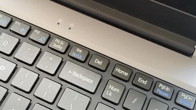 Finger pressing delete button or del key on laptop computer keyboard. User remove, dispose, destroy or erase digital and online electronic recorded file or data fearing privacy and security concern.
