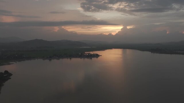 Sunset over Lak Lake in Lien Son Lak Commune, Dak Lak Province, Vietnam, featuring traditional wooden boats on the lake and peaceful rice fields surrounded by the Central Highlands landscape.