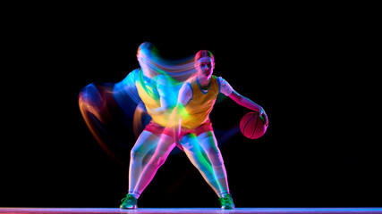 Naklejka premium Focused basketball player in defensive stance with neon motion blur. Concept of defensive training, agility coaching, sport psychology, and modern basketball advertising.