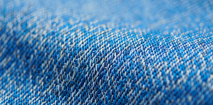 Close-up macro shot of textured blue denim fabric material showing woven threads and detailed fabric pattern with material clothing background close-up abstract backgrounds materialistic