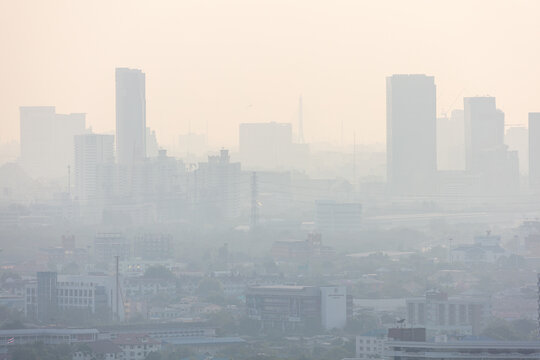 Silhouettes of tall modern city skyscrapers covered in thick toxic smog and heavy air pollution.