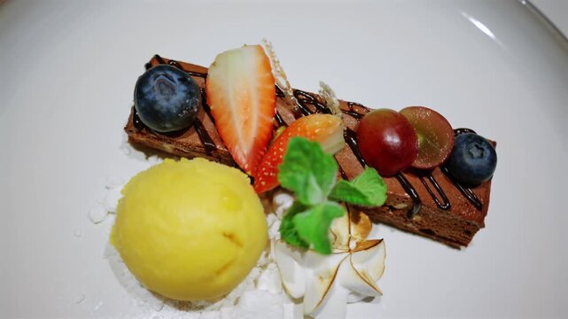 Gourmet chocolate dessert plating with sorbet and fresh fruit garnish.