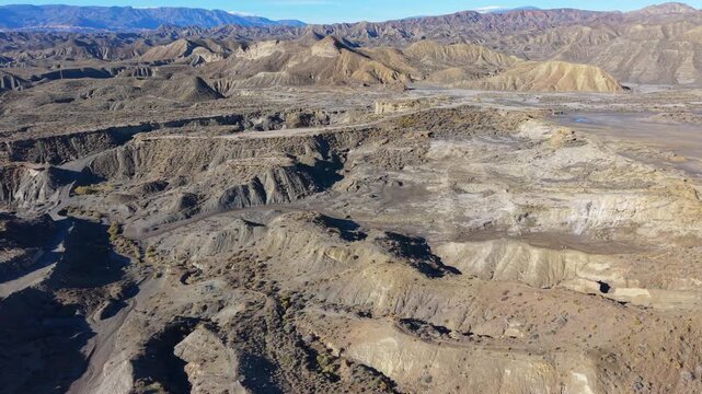 Aerial perspective over the dramatic and arid landscape of the Tabernas Desert in Andalusia, Spain, showing dry riverbeds and badlands
