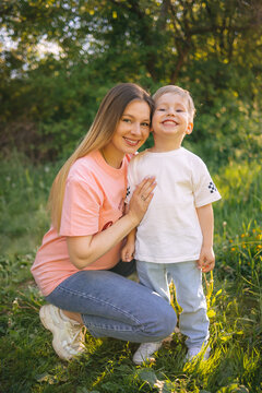 Smiling mother and son embracing outdoors in sunlit park enjoying family moment