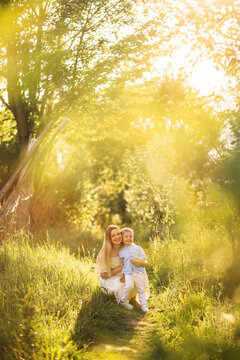 Mother and son smiling together on a sunlit forest path in summer family portrait