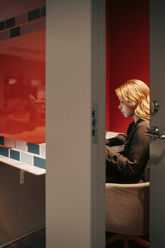 Focused young businesswoman working inside cubicle keeping door ajar