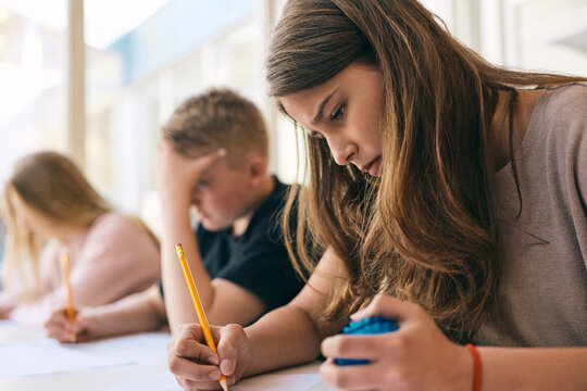 Teenage girl with Autism Spectrum Disorder squeezing stress ball while writing educational exam in school
