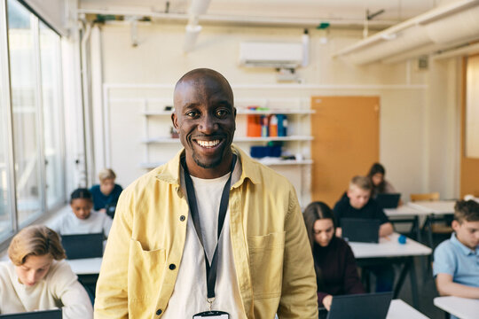 Portrait of smiling teacher standing in classroom at junior high school