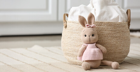 Laundry basket with toy bunny on carpet in room © Pixel-Shot