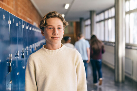 Portrait of junior high male student standing near locker in school lobby