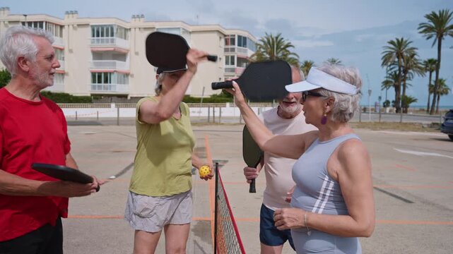 Four senior friends playing pickleball outdoors
