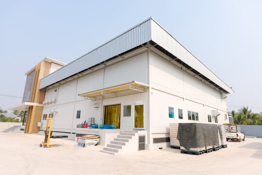 Factory industry modern building outdoor architecture decoration design facade corrugated steel wall against blue sky background manufacturing architecture medium warehouse low angle perspective view.