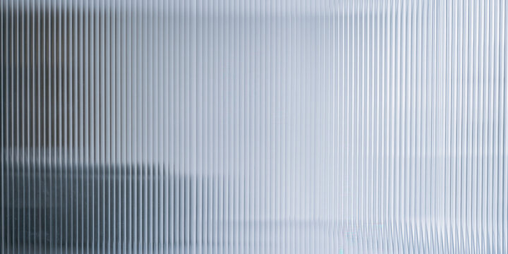 reeded glass texture background featuring vertical smooth linear ridges filtering bright light for minimalist interior design