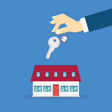 Hand holding key over the house. House buying