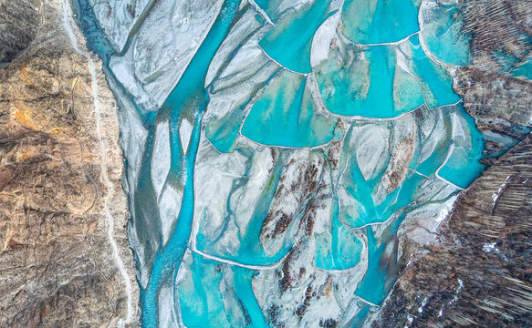Aerial view of the turquoise braided river channels and grey sediment beds near Booni in the mountainous landscape of Chitral, Khyber Pakhtunkhwa, Pakistan.