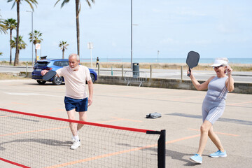 Obraz premium Active senior couple playing pickleball outdoors
